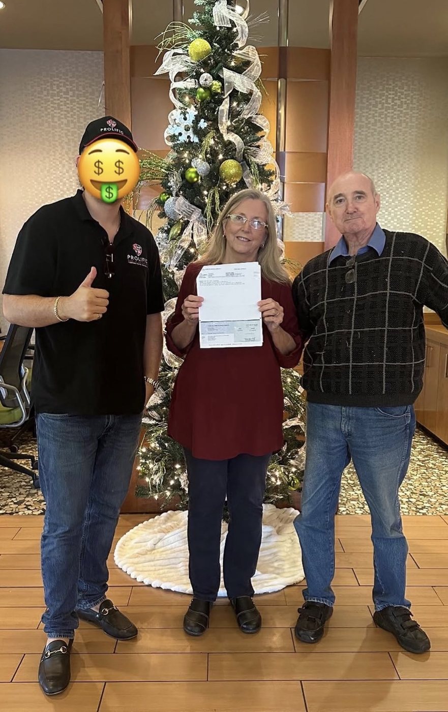 Renato Vallejo of Prolific Public Adjusters with clients holding their settlement check